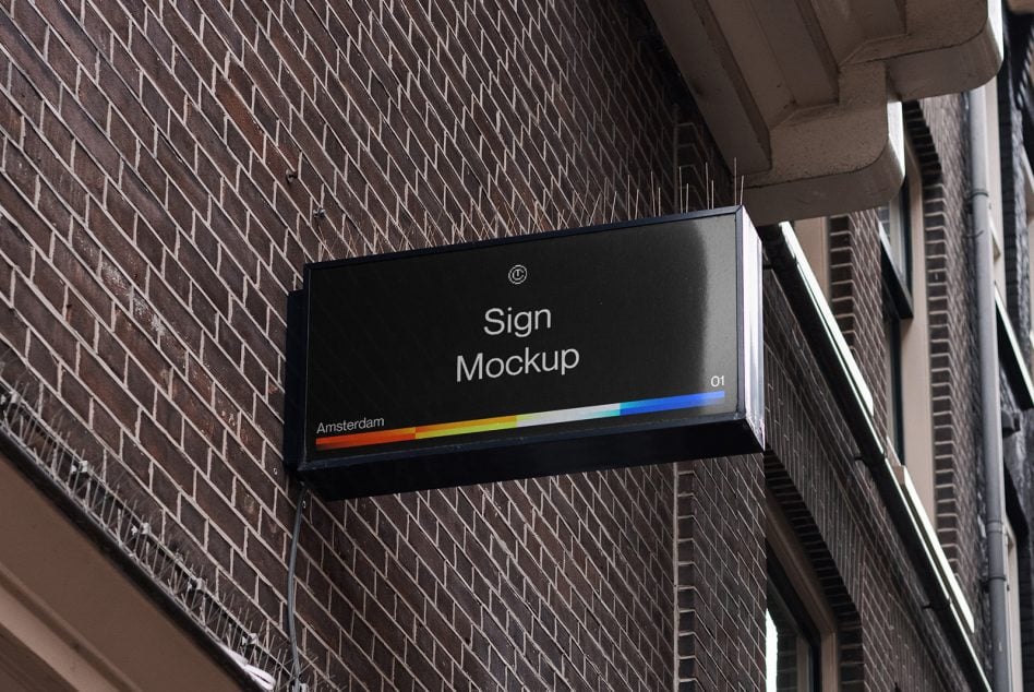 Horizontal black sign on brick wall showing rainbow color gradient stripe
